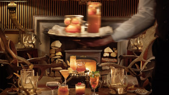 Range of cocktails being served on a table with a waiter and log fire in Edinburgh private restaurant room 