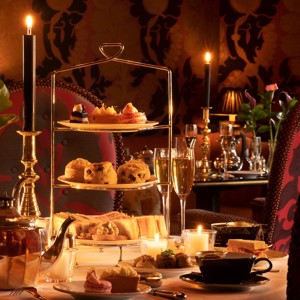 Rhurbarb Edinburgh restaurant table set for luxury afternoon tea with a three-tier stand of pastries, scones, and sandwiches, teapot, teacups, champagne glasses, candles, and flowers