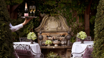 Waiter holds tray with champagne in the Prestonfield House' private dining space Garden Room's terrace 