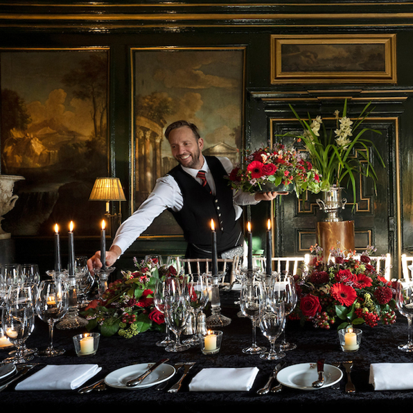 Waiter placing candles and flowers on private dining table in the Italian Room at Prestonfield House 5 star Edinburgh hotel