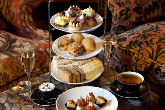 Three-tier stand of sandwiches, scones and pâtisserie served with tea and champagne in the luxurious lounge at Prestonfield House, capturing the indulgent experience of one of the best afternoon teas in Edinburgh